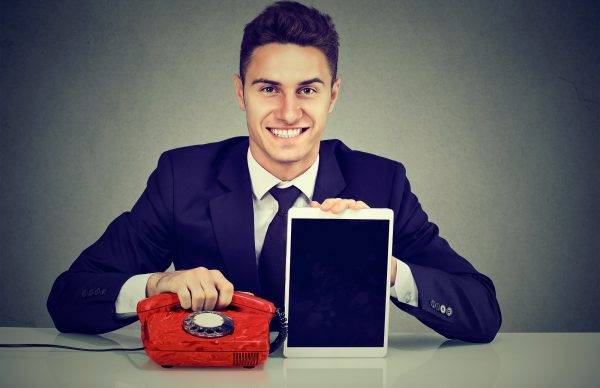 Handsome Business Man Sitting At Desk With Telephone And Tablet Computer