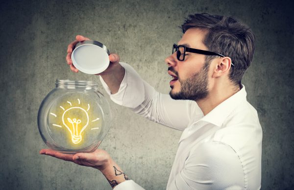 Excited Man Holding Opening A Glass Jar With Bright Idea Lighbulb Inside